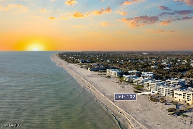 aerial view at dusk featuring a beach view and a water view