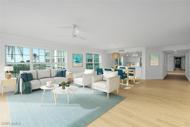 living room with ceiling fan, crown molding, and light hardwood / wood-style floors