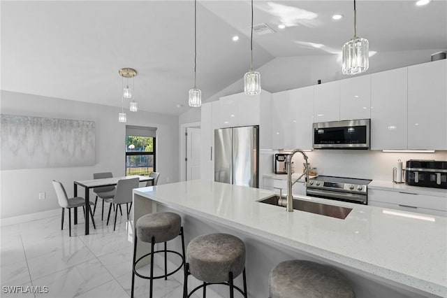 kitchen with vaulted ceiling, appliances with stainless steel finishes, pendant lighting, and white cabinets