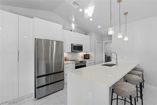 kitchen featuring decorative light fixtures, white cabinetry, lofted ceiling, sink, and stainless steel appliances