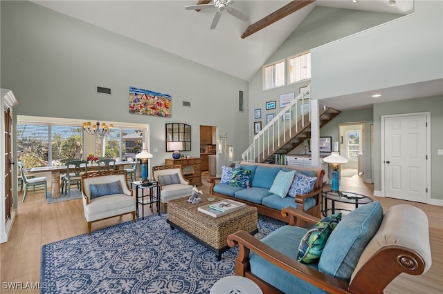 living room with beamed ceiling, ceiling fan with notable chandelier, light hardwood / wood-style floors, and high vaulted ceiling