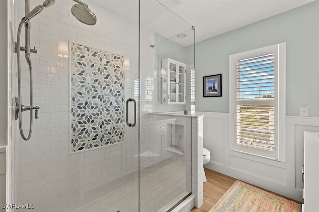 bathroom with hardwood / wood-style floors, toilet, and a shower with shower door