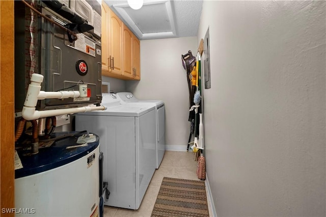 laundry room with cabinets, washing machine and dryer, a textured ceiling, water heater, and light tile patterned flooring