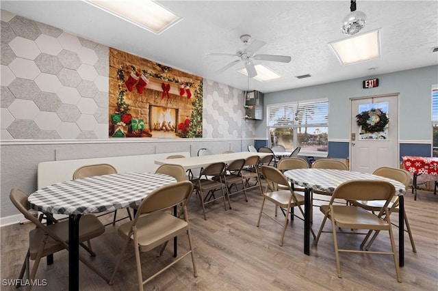 dining space with hardwood / wood-style floors, a textured ceiling, and ceiling fan