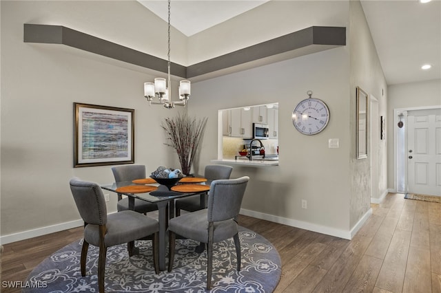 dining room with sink, dark wood-type flooring, and an inviting chandelier