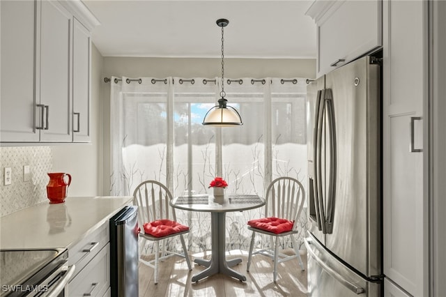 kitchen featuring decorative backsplash, stainless steel fridge, beverage cooler, white cabinets, and hanging light fixtures