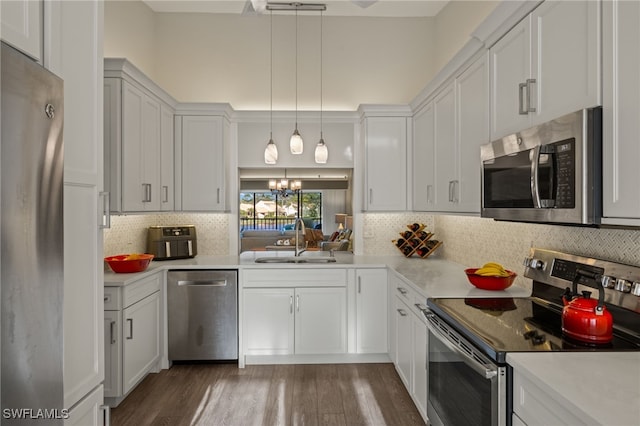 kitchen featuring pendant lighting, sink, dark hardwood / wood-style flooring, white cabinetry, and stainless steel appliances