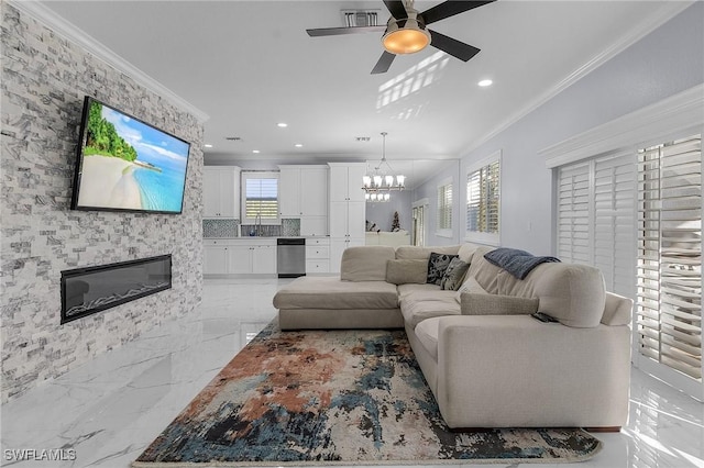 living room with ceiling fan with notable chandelier, ornamental molding, and a fireplace