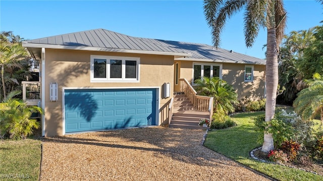 ranch-style home featuring an attached garage, a standing seam roof, metal roof, and stucco siding