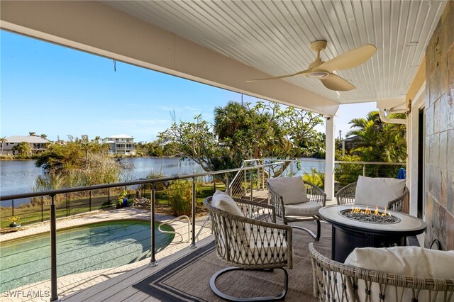 deck featuring ceiling fan, a water view, and an outdoor fire pit