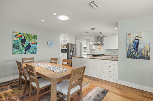 dining space with sink and light hardwood / wood-style flooring