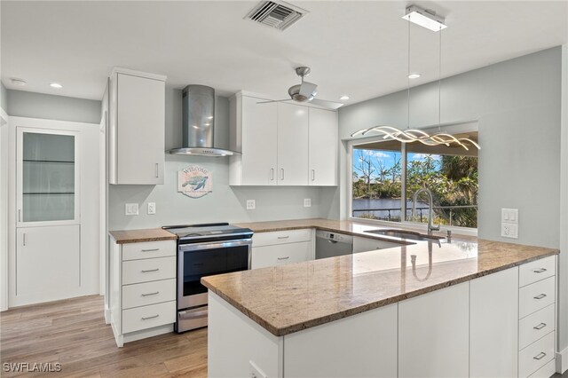 kitchen featuring stainless steel appliances, ceiling fan, wall chimney exhaust hood, sink, and white cabinetry