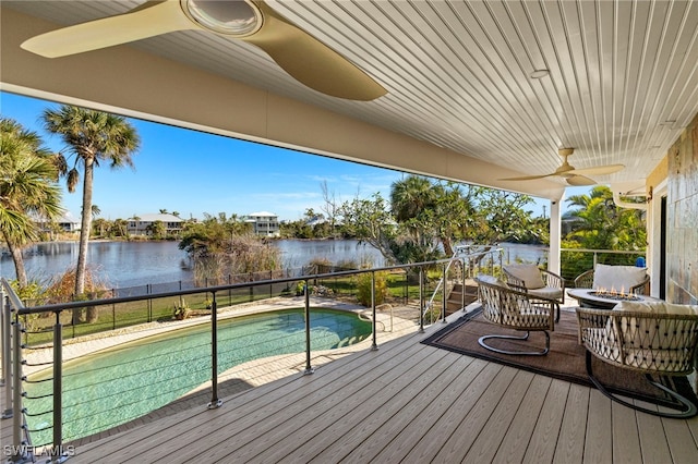 deck with an outdoor fire pit, a fenced in pool, and a water view