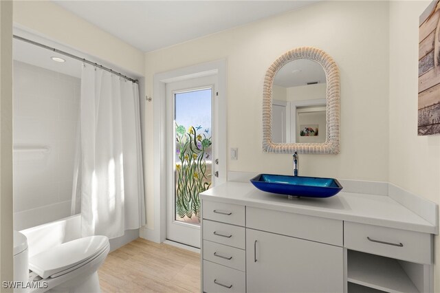 full bathroom with toilet, vanity, hardwood / wood-style floors, and shower / tub combo with curtain