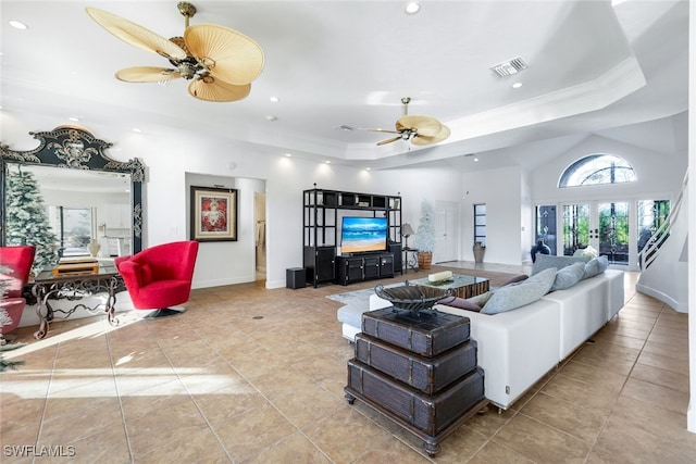 living room featuring light tile patterned floors, visible vents, a ceiling fan, a raised ceiling, and crown molding