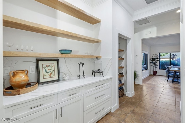 bar with light tile patterned floors, visible vents, decorative backsplash, ornamental molding, and baseboards