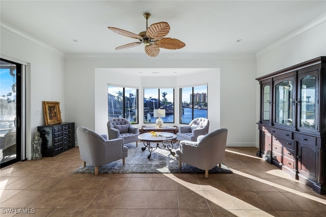 living room featuring ceiling fan, dark tile patterned floors, a water view, baseboards, and ornamental molding