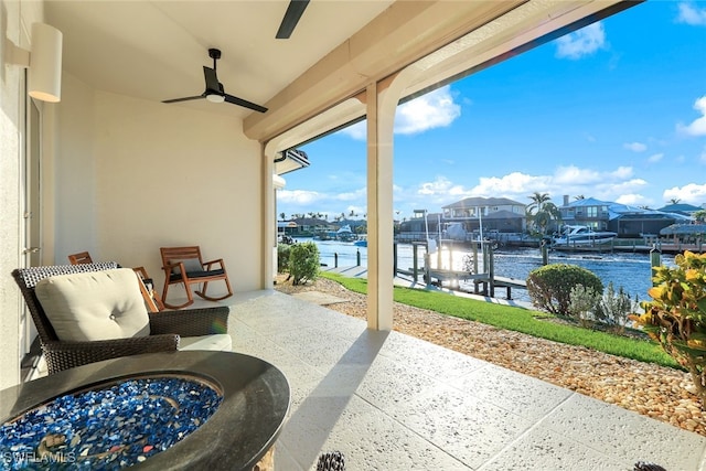 view of patio with a boat dock, a water view, and a ceiling fan