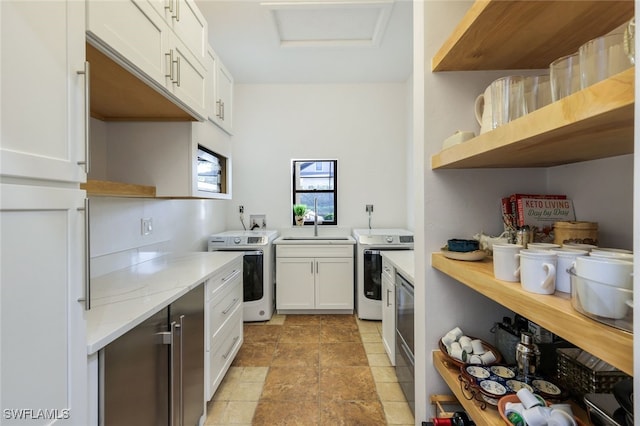 kitchen with independent washer and dryer, white cabinets, a sink, and open shelves