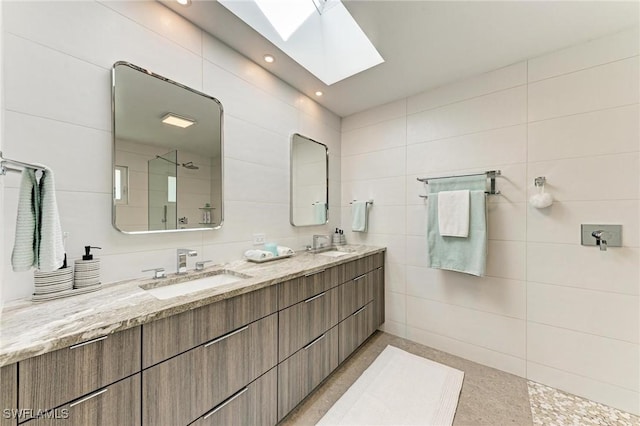 bathroom with a skylight, a shower, vanity, and tile walls