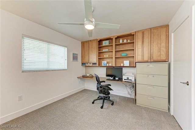 carpeted office with ceiling fan and built in desk