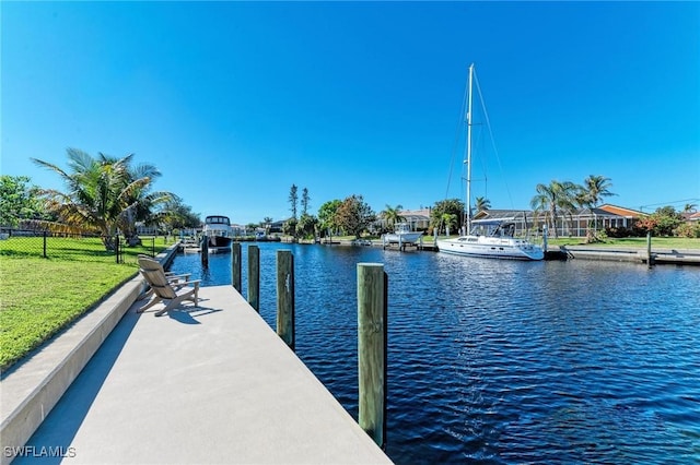 view of dock with a lawn and a water view