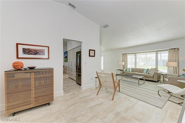 tiled living room with a textured ceiling and vaulted ceiling