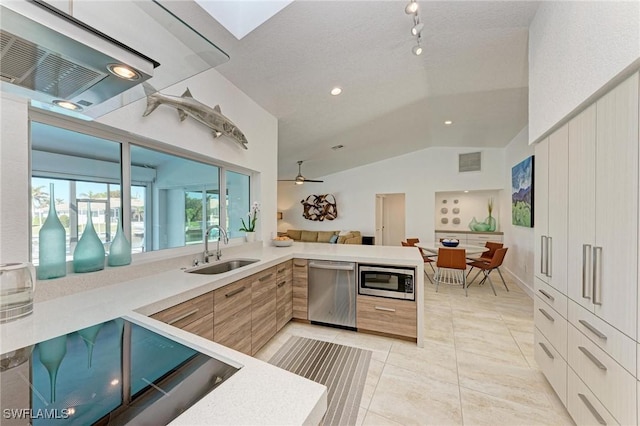 kitchen featuring kitchen peninsula, appliances with stainless steel finishes, vaulted ceiling, ceiling fan, and sink