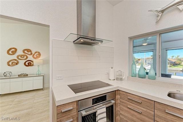 kitchen with stainless steel oven, tasteful backsplash, light tile patterned floors, black electric stovetop, and wall chimney range hood