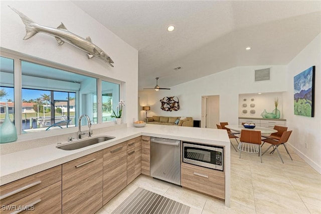 kitchen with kitchen peninsula, stainless steel appliances, ceiling fan, sink, and lofted ceiling