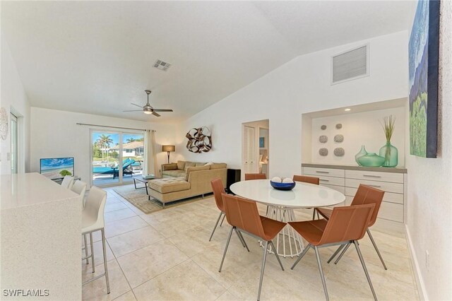 tiled dining space with ceiling fan and vaulted ceiling