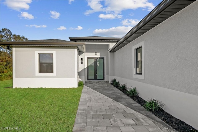 doorway to property with a lawn and french doors