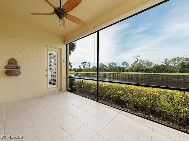 unfurnished sunroom featuring ceiling fan and a water view