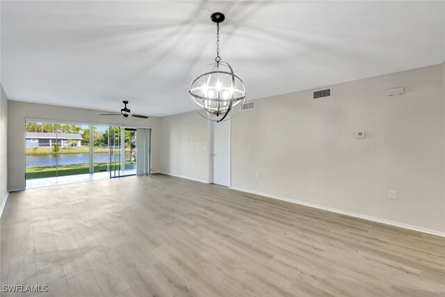 unfurnished room featuring ceiling fan with notable chandelier, light hardwood / wood-style flooring, and a water view