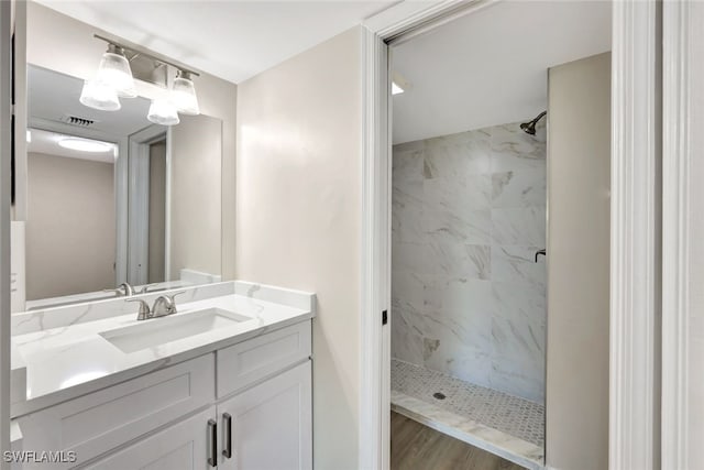 bathroom featuring a tile shower and vanity