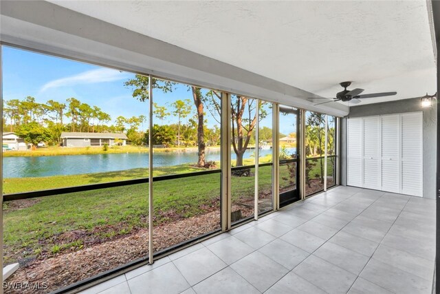 unfurnished sunroom featuring ceiling fan and a water view