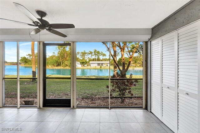 unfurnished sunroom with ceiling fan, a healthy amount of sunlight, and a water view