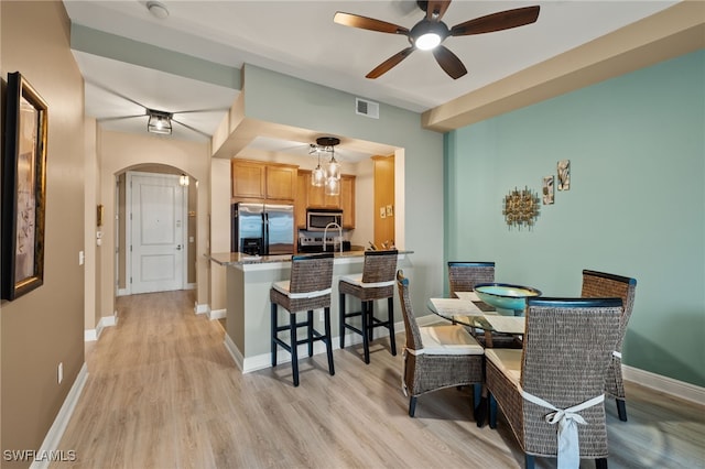 dining room with light hardwood / wood-style flooring and ceiling fan with notable chandelier