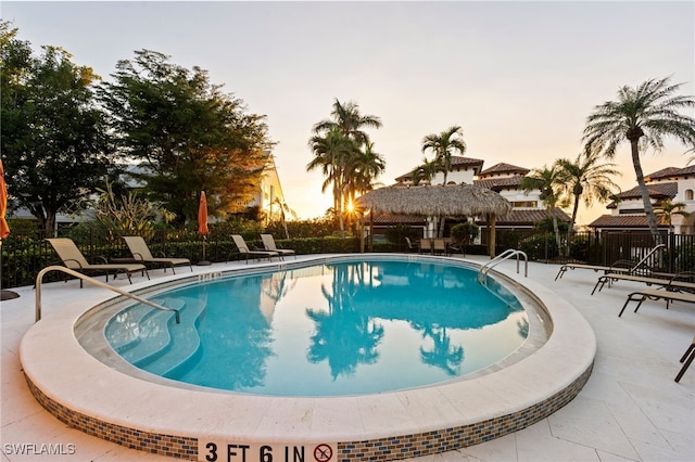 pool at dusk with a gazebo and a patio area