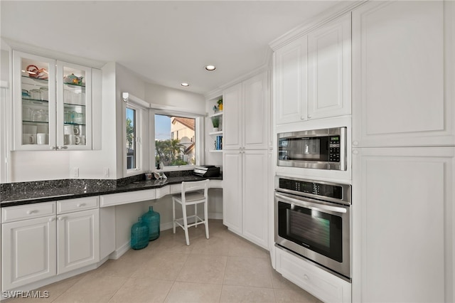 kitchen with light tile patterned flooring, dark stone countertops, white cabinetry, and appliances with stainless steel finishes