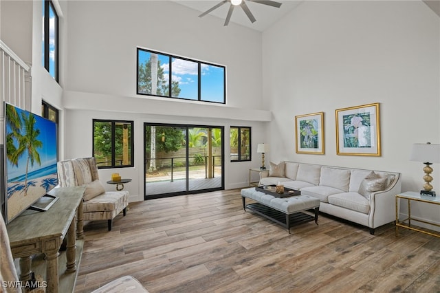 living room with ceiling fan, light wood-type flooring, and high vaulted ceiling