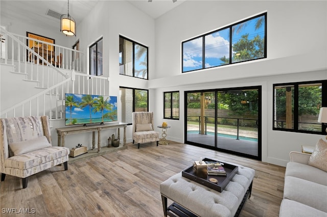 living room with a healthy amount of sunlight, wood-type flooring, and a high ceiling