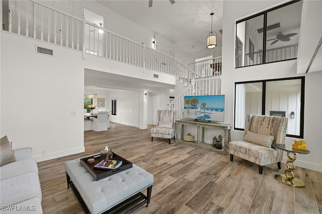 living room featuring ceiling fan, hardwood / wood-style floors, a healthy amount of sunlight, and a high ceiling