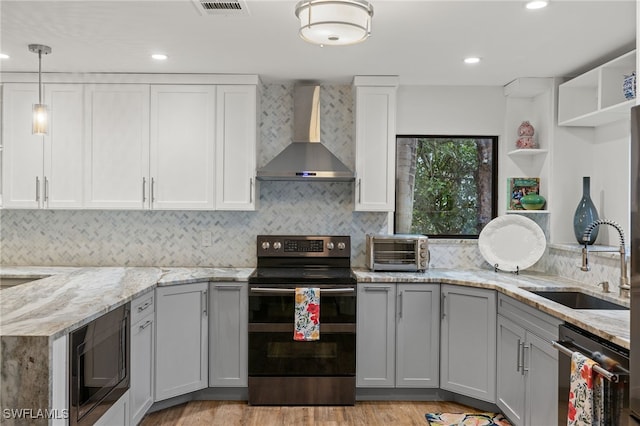 kitchen featuring light stone countertops, sink, wall chimney range hood, and appliances with stainless steel finishes