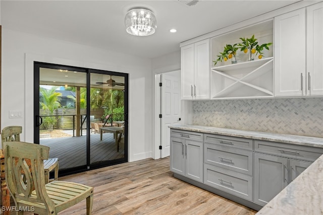 kitchen featuring gray cabinets, light stone countertops, backsplash, and light hardwood / wood-style flooring