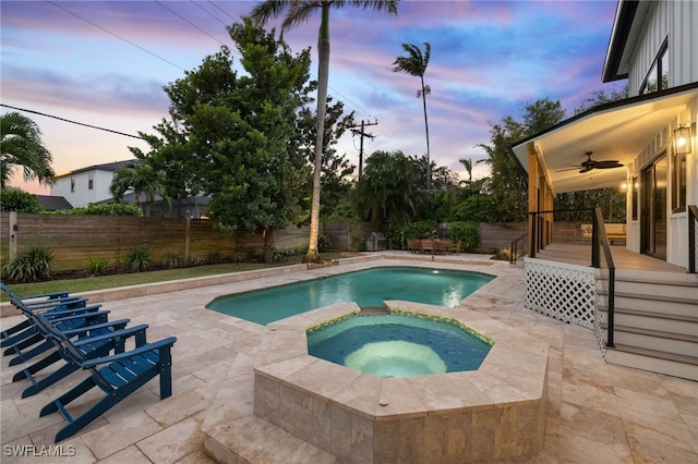 pool at dusk featuring an in ground hot tub, ceiling fan, and a patio