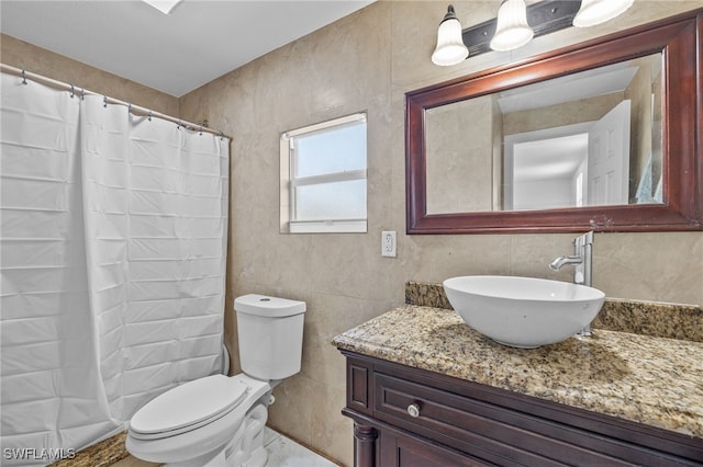 bathroom featuring walk in shower, vanity, toilet, and tile walls