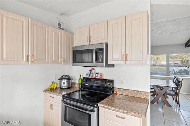 kitchen featuring black electric range, light brown cabinets, a textured ceiling, and light tile patterned flooring