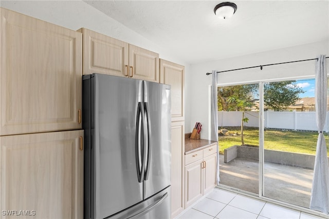 kitchen with stainless steel refrigerator, light brown cabinetry, and light tile patterned flooring