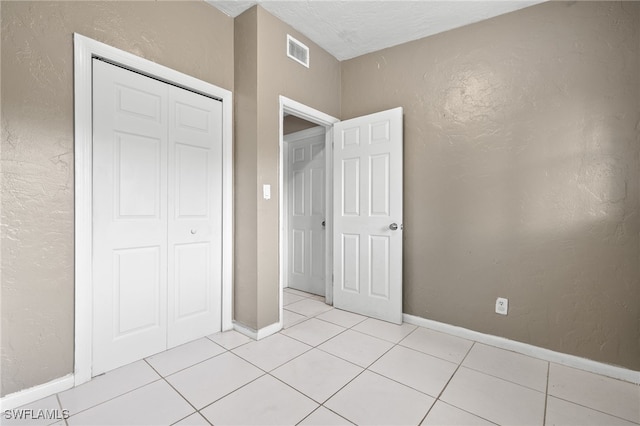 unfurnished bedroom with light tile patterned flooring and a closet